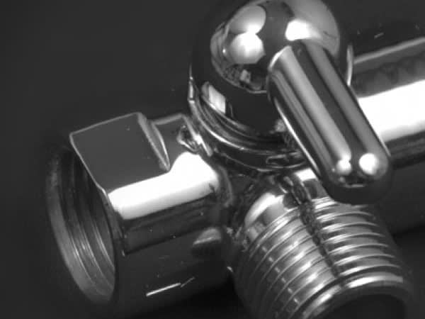 Close-up of a polished chrome 3 way shower head diverter valve with a lever handle.